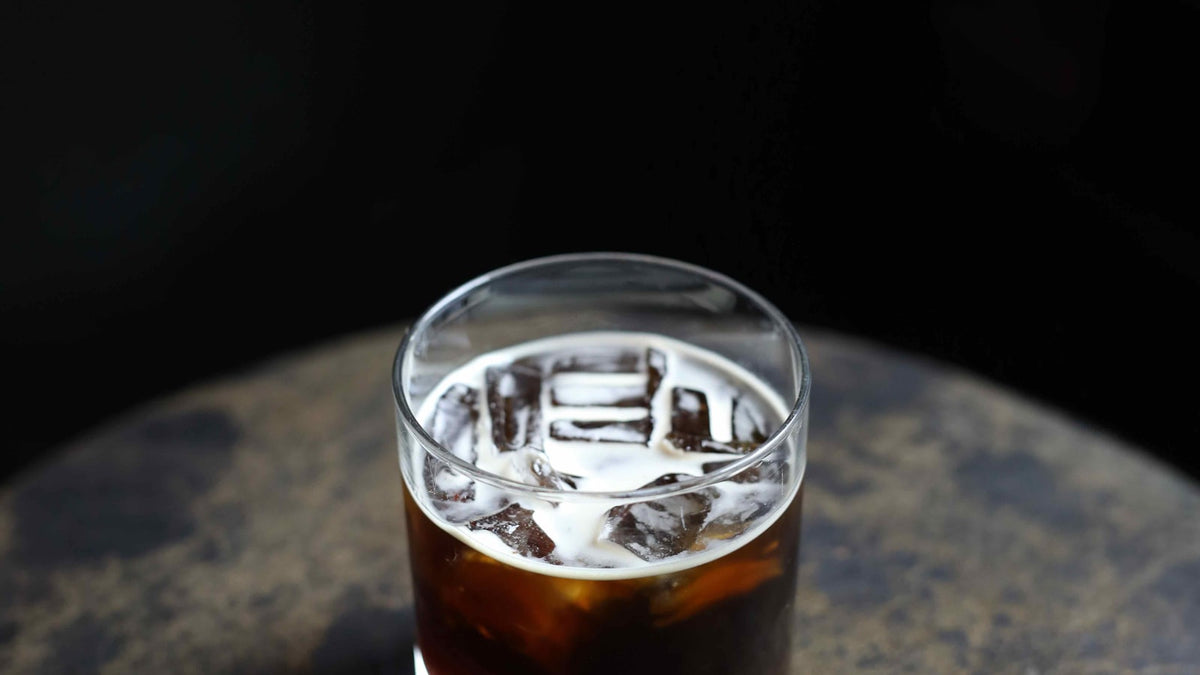 A glass of iced coffee on a brown stone surface